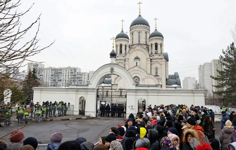 Gente reunida frente a la iglesia donde se celebrará el entierro